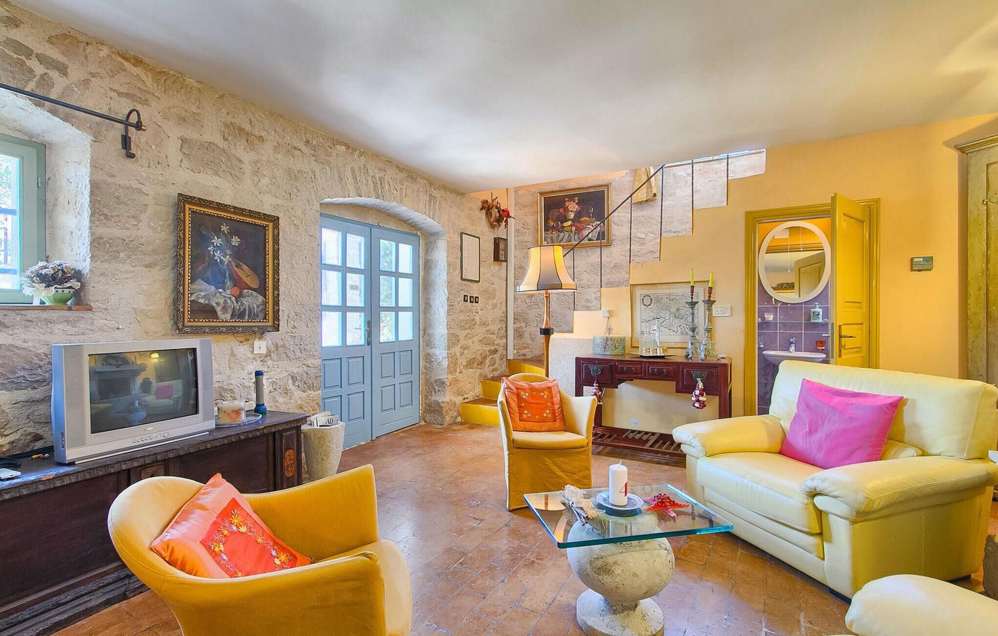 A cozy living room with a stone wall, a television, a sofa, and a coffee table.