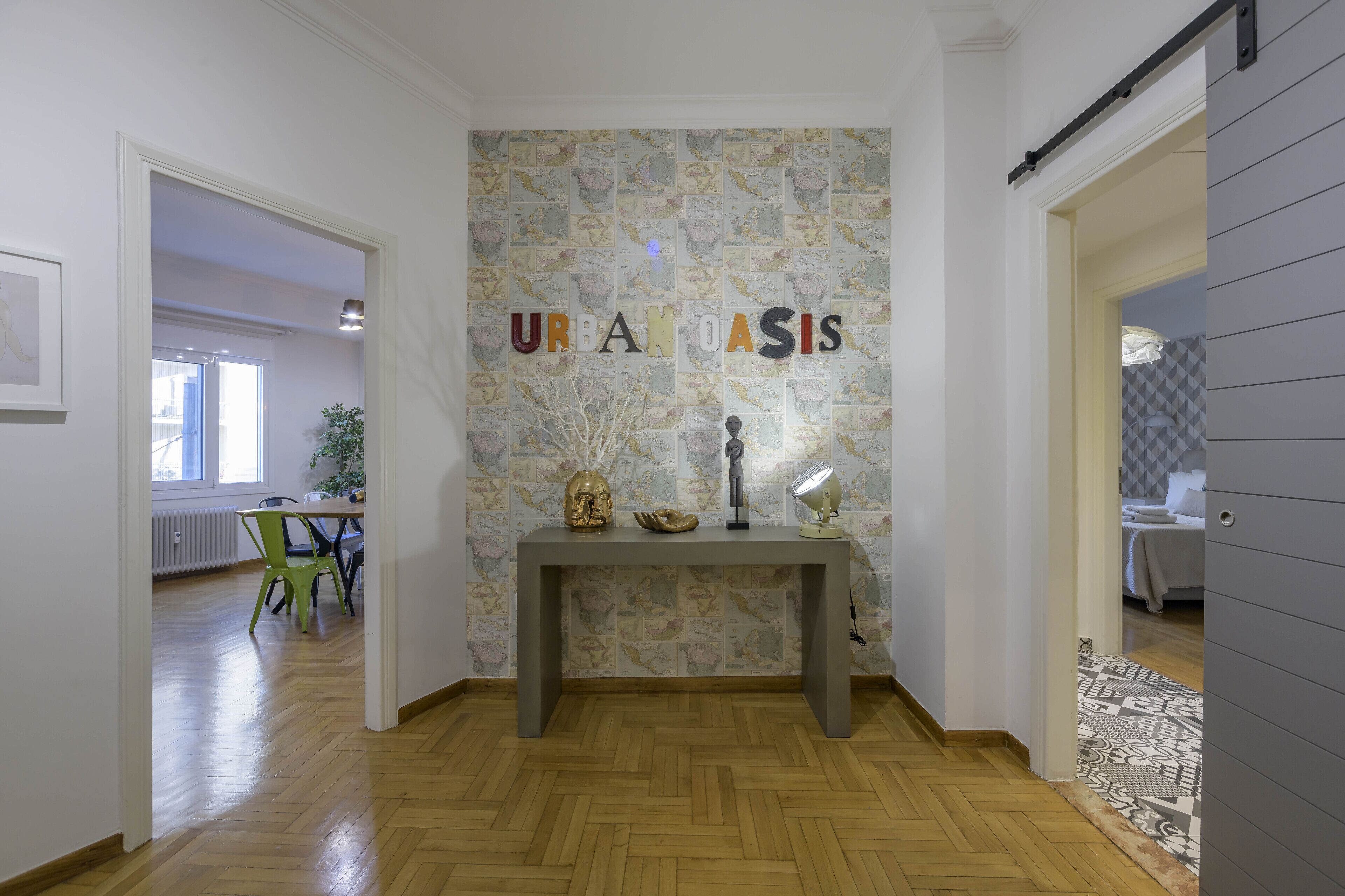 A hallway with a herringbone floor, a grey sliding door, and a wall with the text "URBAN OASIS".