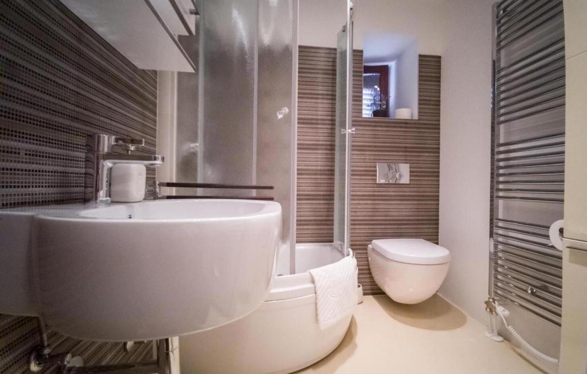 A modern bathroom with a large sink, a shower enclosure, and a toilet.