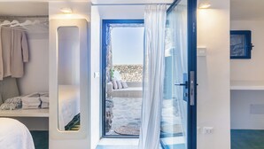 Un dormitorio moderno con un espejo grande, una cama bien hecha y vistas a una pared de piedra exterior.