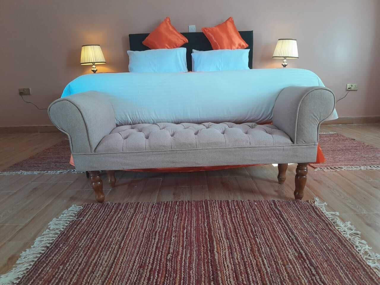 Une chambre à coucher avec un lit, deux lampes de chevet et un canapé gris recouvert de tissu.