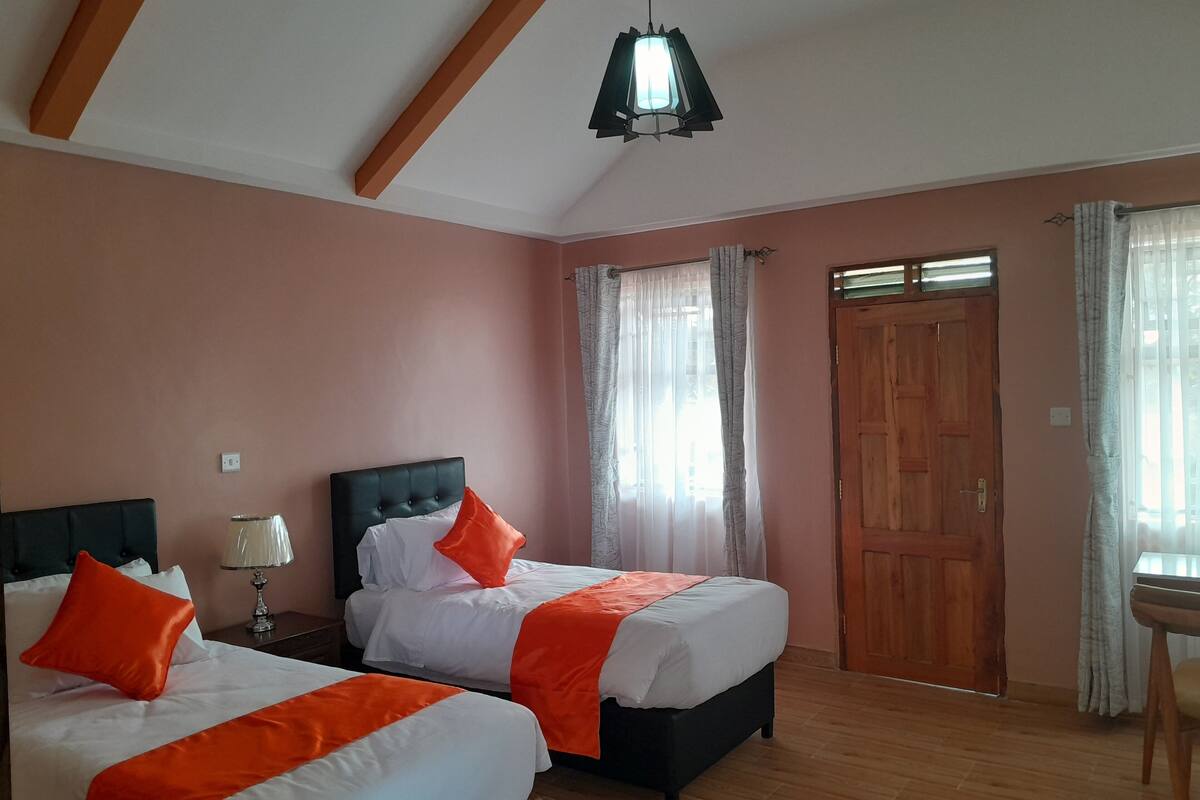 Un dormitorio con dos camas, una puerta de madera y un colgante de luz.