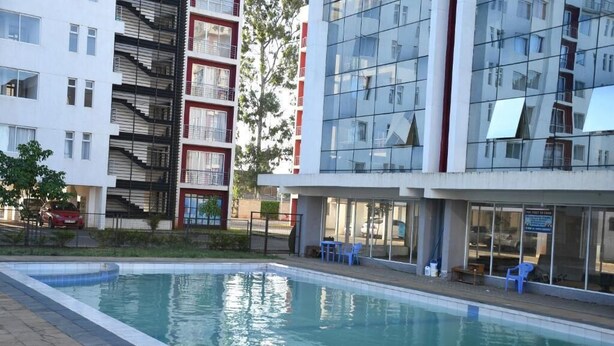 Zona de piscina amb un edifici modern al fons.