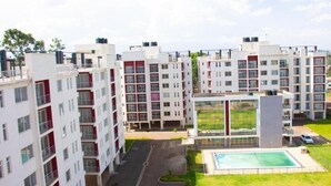 Un complex d'apartaments modern amb diversos edificis, un pati central amb piscina i una zona verda ben cuidada.