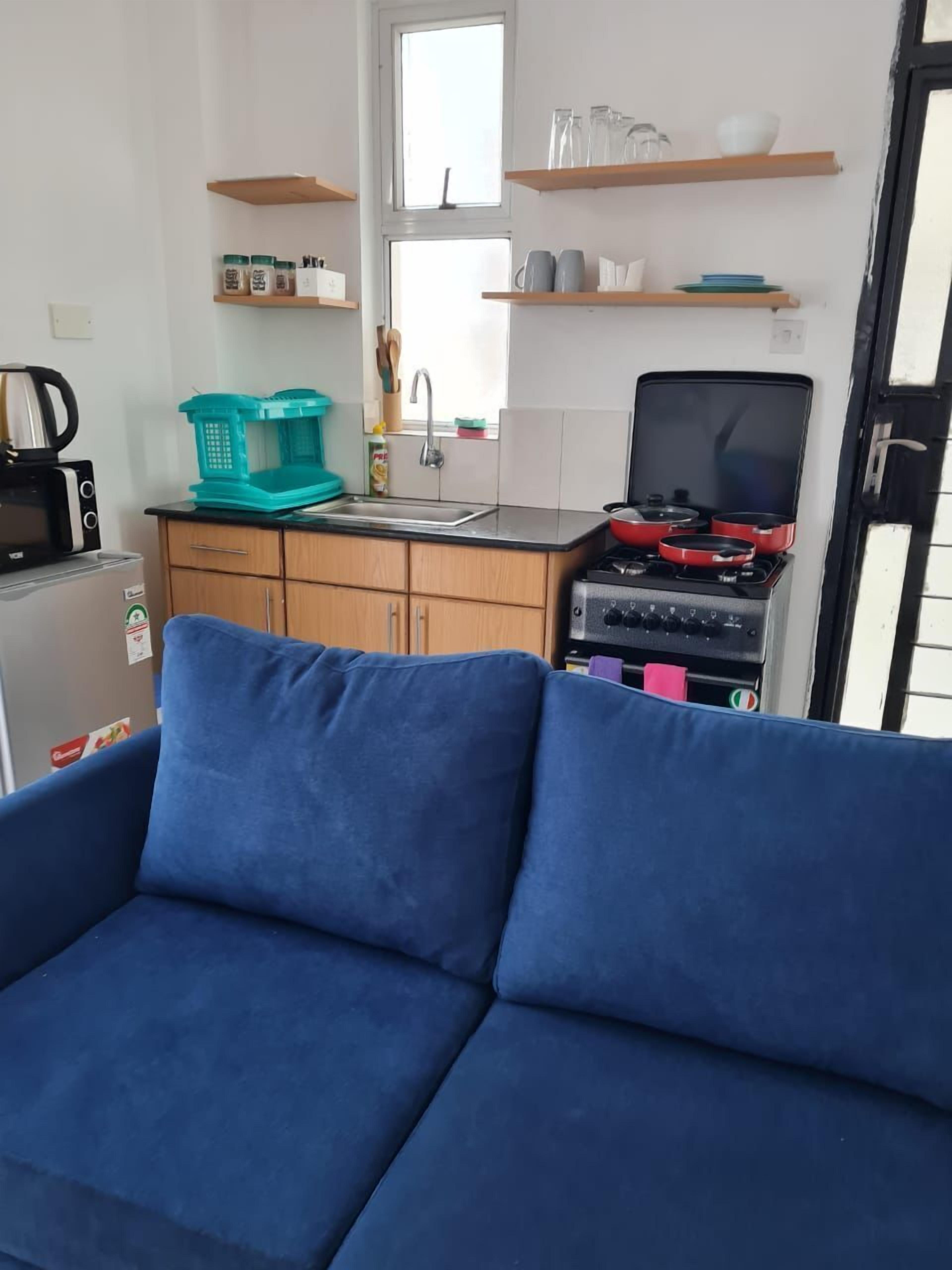Un espacio habitable pequeño con kitchenette, un sofá y una ventana.