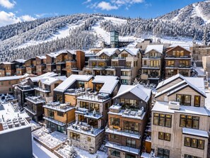 A snow-covered resort with modern buildings, balconies, and a ski slope in the background. - Kings Crown Ski-In/Out•Private Hot Tub•Walk to Main (Park City)