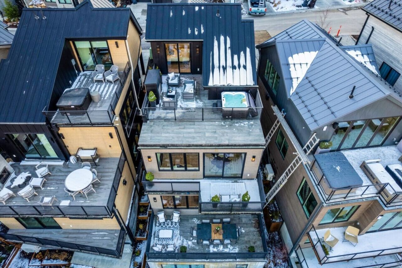 A modern multi-story building with outdoor seating areas, a rooftop pool, and large windows.