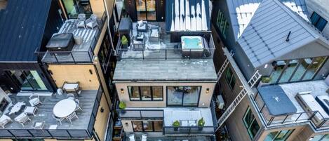 A modern multi-story building with outdoor seating areas, a rooftop pool, and large windows.