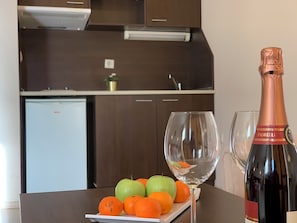Uma cozinha com armários de madeira escura, bancada branca e uma garrafa de champanhe Fiolelli.