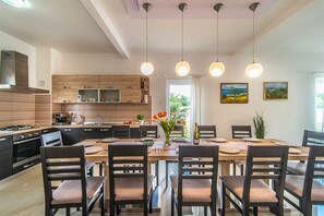 Una cocina moderna con zona de comedor, armarios de madera, estufa e iluminación colgante.