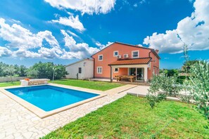 Una casa de dos pisos con piscina, un patio y jardín.