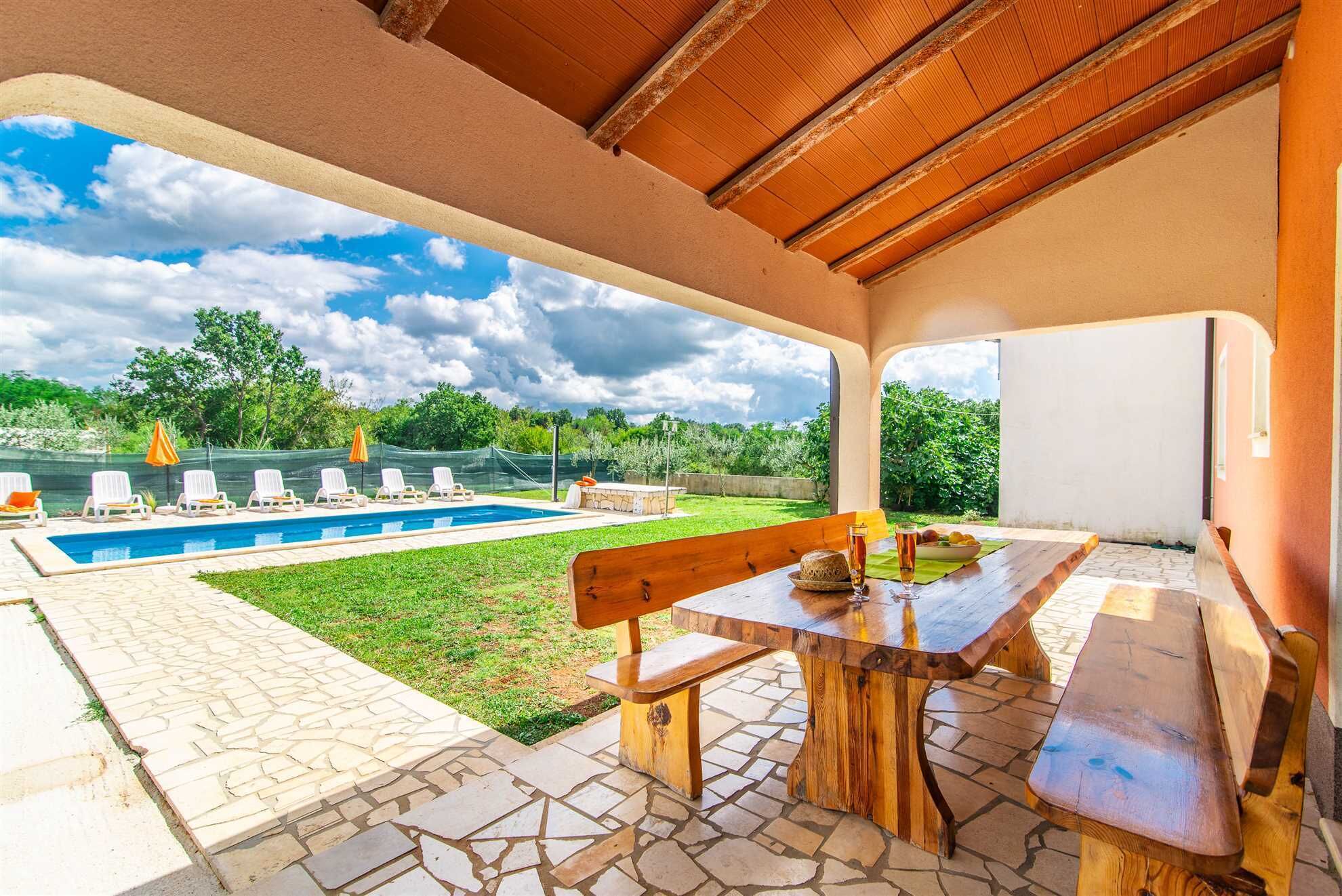 Une terrasse extérieure avec une piscine, des chaises longues et une table en bois.
