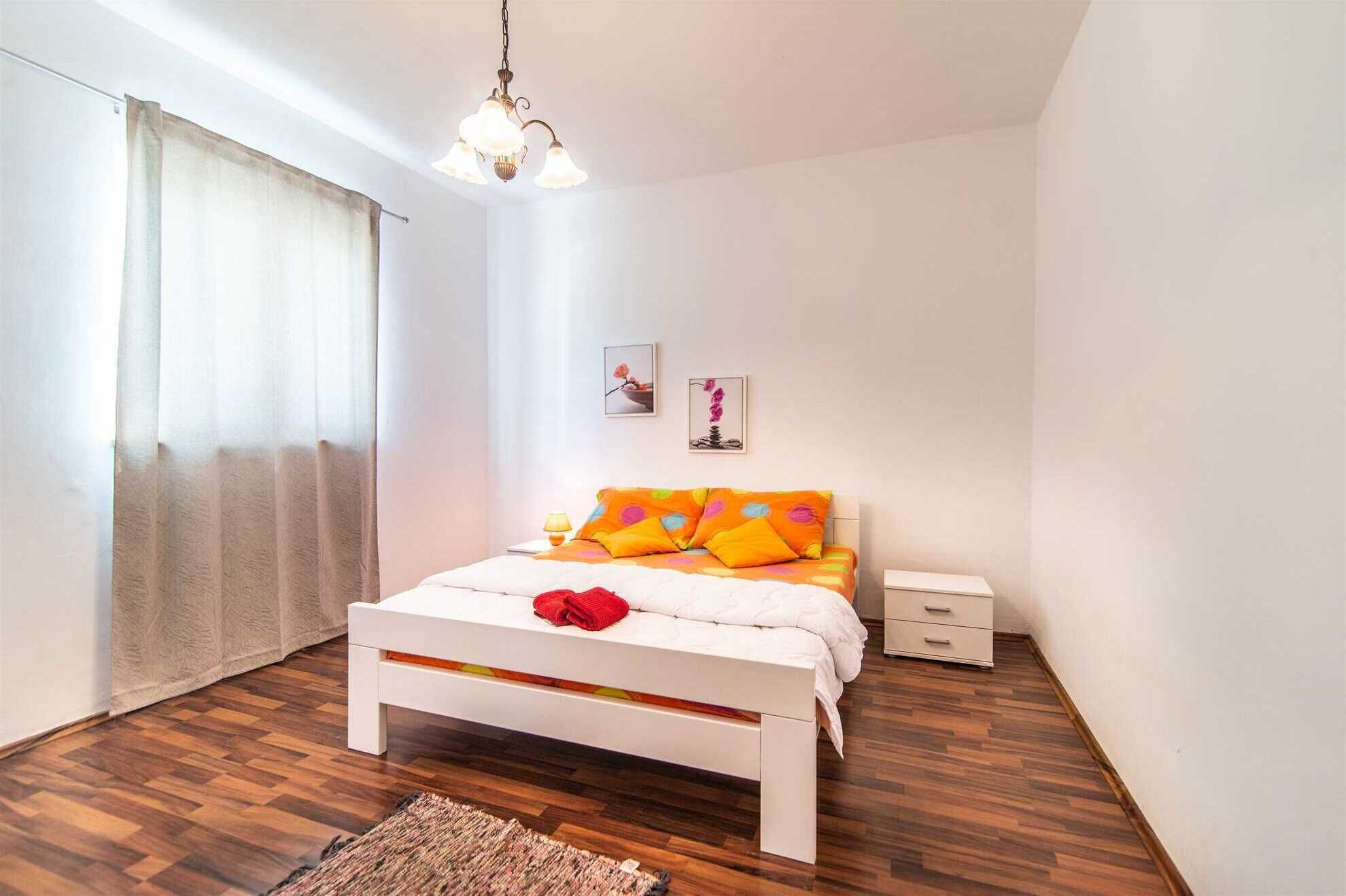 A bedroom with a bed, bedside table, lamp, and a hanging light fixture.