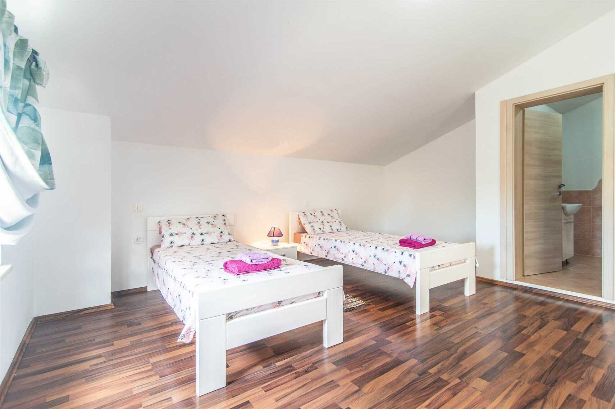 A bedroom with two beds, a bedside table with a lamp, and a mirror.
