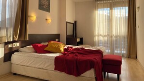 A hotel room with a bed, a bedside table, a lamp, a mirror, and a window with curtains. - Banderitsa Apartment 3 (Bansko)