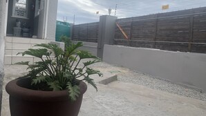 A potted plant on a concrete step, a building entrance with a sign, and a wooden fence with a sign. - Kingsworth Inn - Port Elizabeth (Gqeberha (Port Elizabeth))