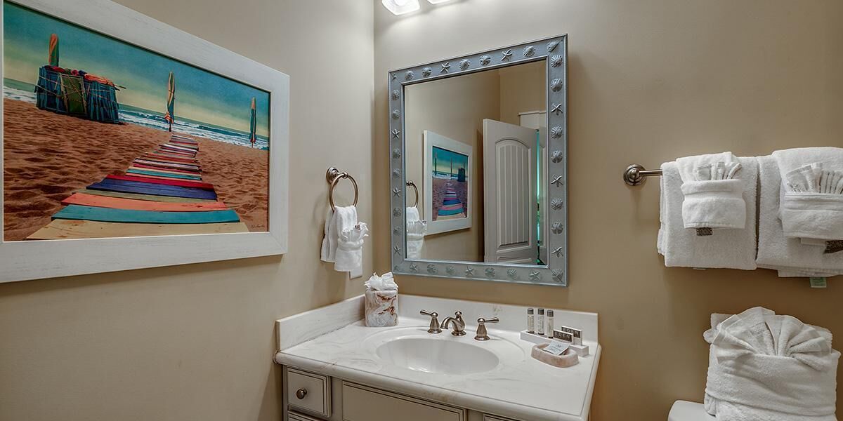Une salle de bain avec un grand miroir, un lavabo et un porte-serviettes.
