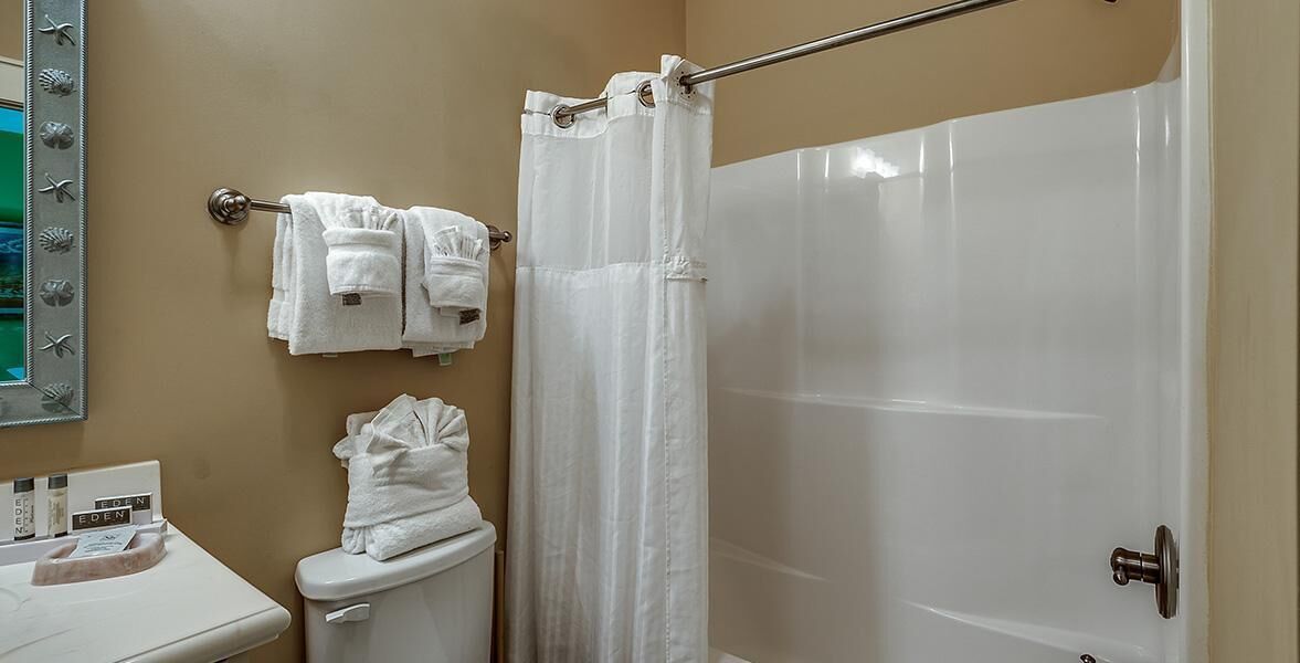 A bathroom with a toilet, a shower curtain, and a towel rack with towels.