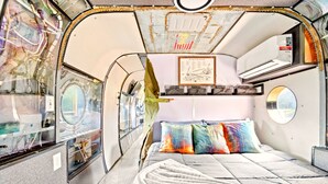Ein kompakter, futuristischer Innenraum mit Etagenbett, kleinem Tisch und einem gerahmten Stadtplan an der Wand.