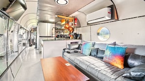 Eine kompakte Küche mit modernen Geräten, ein Sofa mit bunten Kissen und ein kleiner Esstisch.
