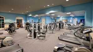 Un gimnasio con diversos equipos de ejercicio, incluyendo cintas de correr, elípticas y máquinas de pesas.