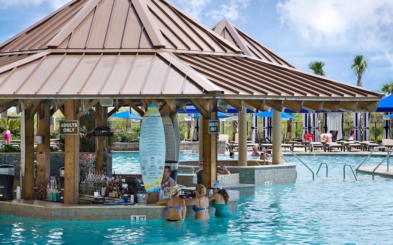 Un área de piscina con bar y sillones de descanso.