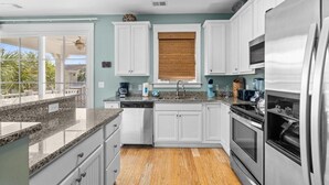 A kitchen with white cabinets, a stainless steel refrigerator, and a wooden floor. - Unwind in Style: Luxury 2 Bdrm Townhome Sleeps 8 (North Myrtle Beach)