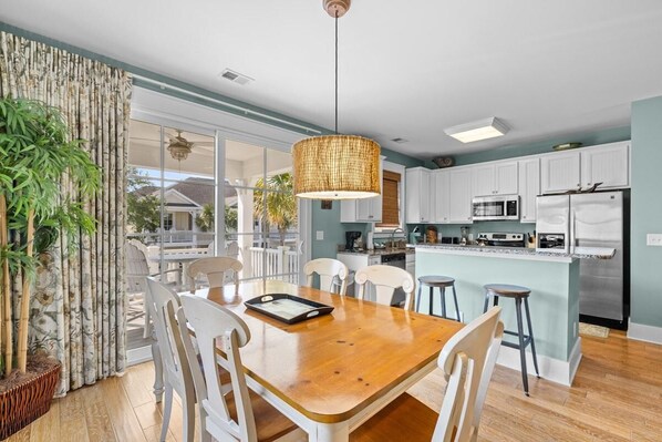 Una cocina moderna con armarios blancos, electrodomésticos de acero inoxidable y una mesa de comedor de madera con sillas.