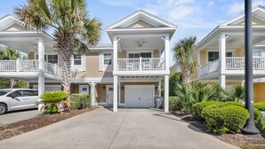 A multi-story residential building with a covered front porch, a garage, and a well-maintained lawn. - Unwind in Style: Luxury 2 Bdrm Townhome Sleeps 8 (North Myrtle Beach)