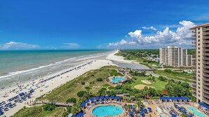 Un complejo turístico en la playa con una piscina grande, playa y edificios altos.
