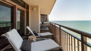 Ein Balkon mit zwei Lounge-Stühlen, einem kleinen Tisch und Blick auf den Ozean.