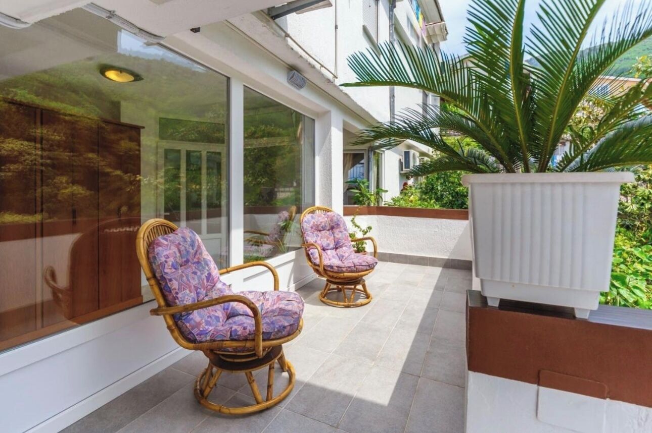 A balcony with wicker chairs and a potted plant.