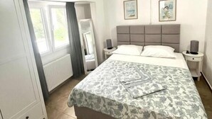 A bedroom with a bed, nightstands, a wardrobe, and a window. - Apartments Harmonija  (Becici)