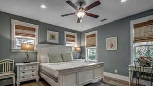 Une chambre à coucher comprenant un lit, des tables de chevet, un bureau et une chaise.