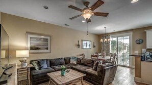 A living room with a sectional sofa, a wooden coffee table, and a ceiling fan.