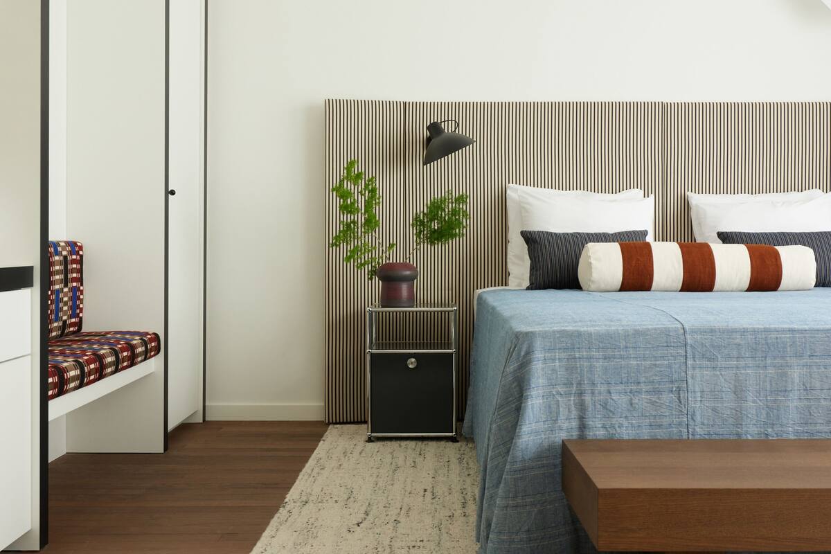 A modern bedroom with a bed, bedside table, and a bench.