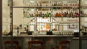 A bar area with multiple shelves of liquor bottles, glasses, and a bar counter with stools. - Morgan & Mees Rotterdam (Rotterdam)