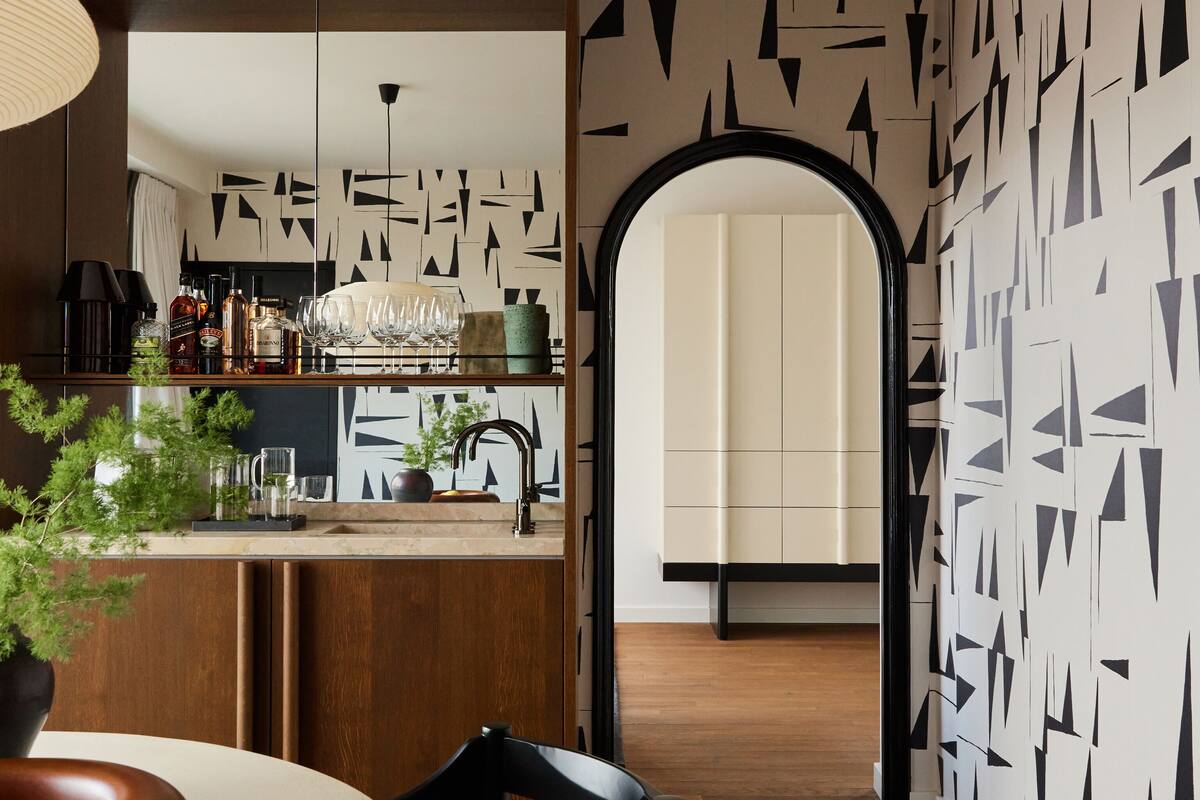 A modern kitchen with a bar area, wooden cabinets, and a dining table with chairs.