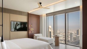 A modern hotel room with a large bed, a seating area, a TV, and a city view. - SIRO One Za'abeel (Dubai)