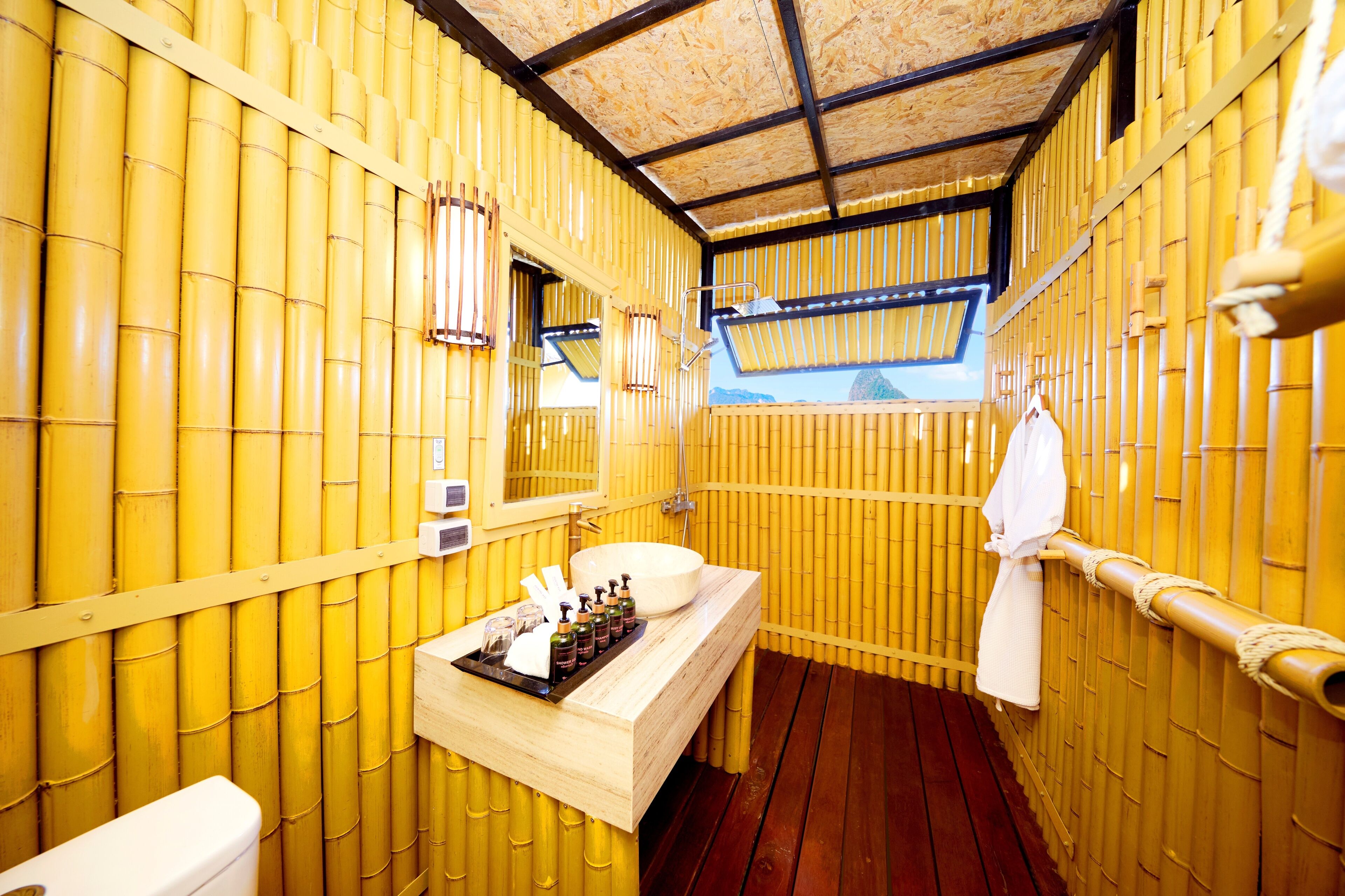 A bathroom with bamboo walls, a wooden vanity, a sink, a mirror, and a towel rack.