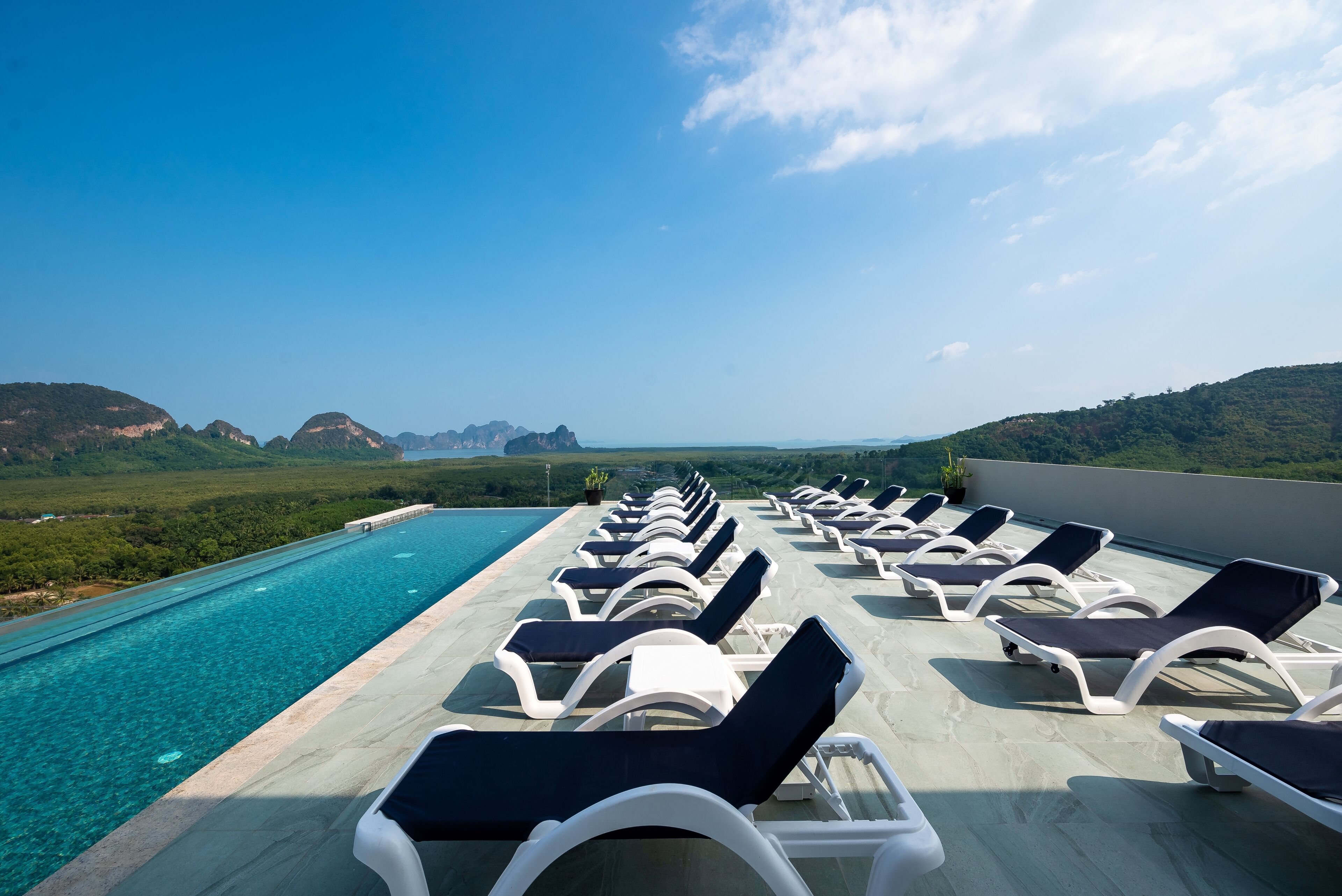 A rooftop pool area with lounge chairs and a clear view of the surrounding landscape.