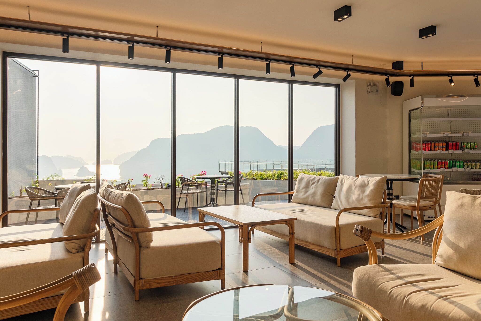 Un salon moderne doté de grandes fenêtres, de meubles en osier et offrant une vue sur les montagnes.