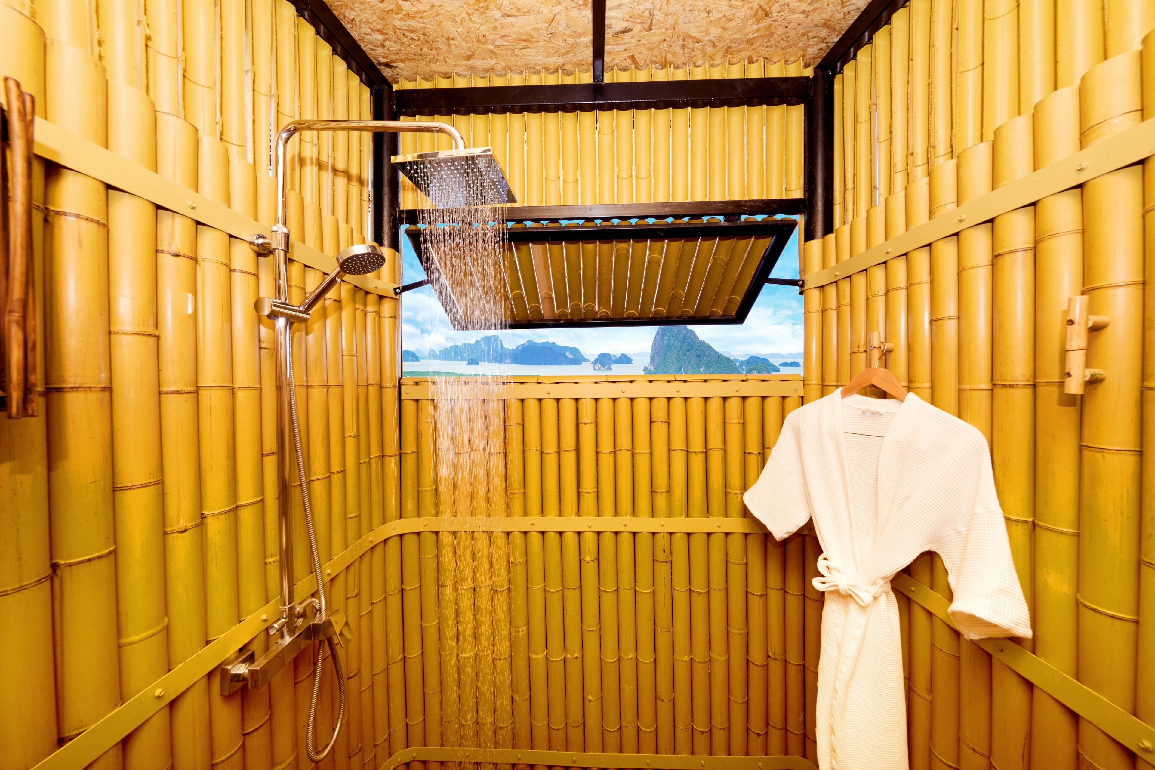 A room with a bamboo wall, a shower area, and a view of mountains.