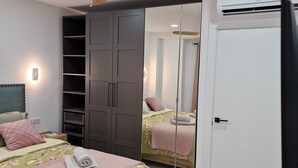 Quarto com cama, guarda-roupa, espelho e ar condicionado.