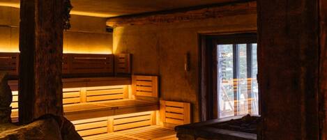 A rustic interior with wooden benches, a stone wall, and a window.