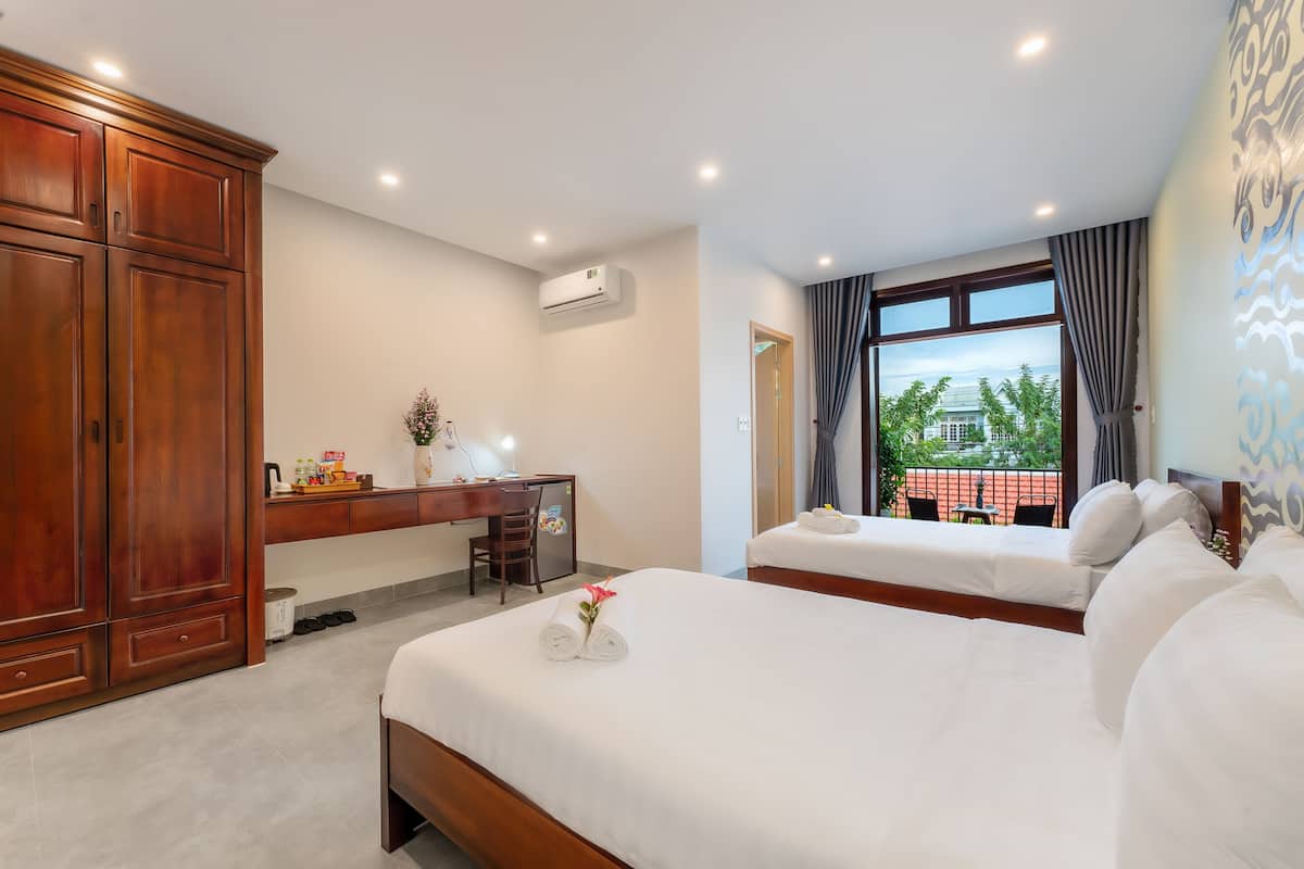 A hotel room with two beds, a desk, and a large wardrobe.