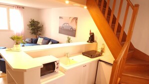 A compact kitchen with a built-in microwave, sink, and small refrigerator. A wooden staircase leads to another level.