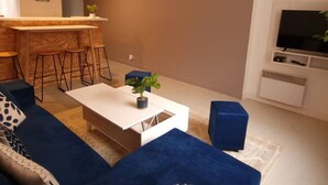A modern living room with a sofa, coffee table, and bar stools.