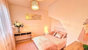 Une chambre à coucher comprenant un lit, une table de chevet, une lampe et une œuvre d’art accrochée au mur.
