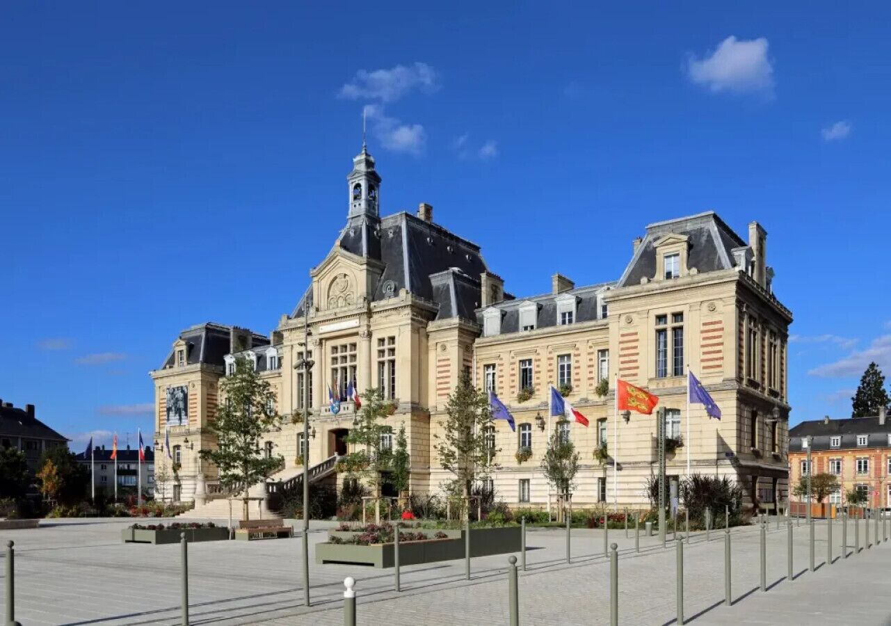 Een historisch gebouw met klassieke architectuur, voorzien van een centraal klokkentoren, meerdere vlaggen en een ruime binnenplaats.